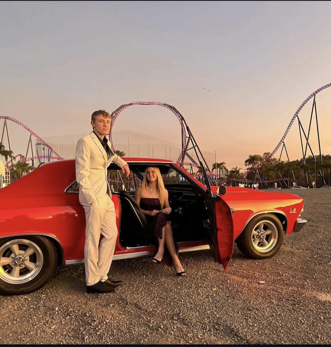 Formal couple with the Chevelle, roller coasters behind